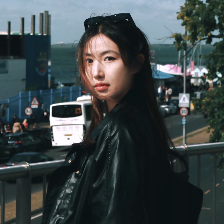 Heqing Yang standing outdoors in a black leather jacket